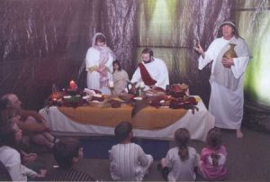 Jonathan Thomas (center) prepares the table for the Lord’s supper, part  of the Journey to Easter of several years ago. He will be directing the Journey this year which will be at the American Legion Hut in Edgefield.