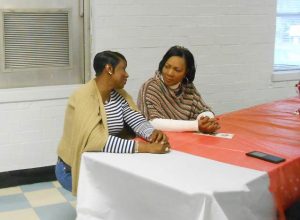 Two mothers of NFL players, Tracey Hamilton and Angela Watson, confer at the meeting of ECYEC in Johnston after bringing Christmas to a group of children in the Center.  Their sons, Jakar and Dakoda respectively, play for the Dallas Cowboys.