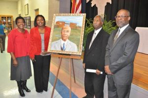 Speakers and Board members at the W.E. Parker event gather around the portrait following the unveiling: L. to R., Sally Cooks, former board member; Latoya Hammond, speaker and board member; Willie Campbell, board member and gave the benediction; and James Bibbs, speaker and board member. 