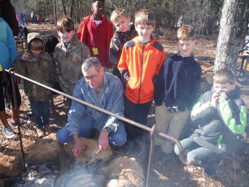 Keith Sexton surrounded by area home schooled students as he roasts sausage on an open fire at the Battle of Aiken. 